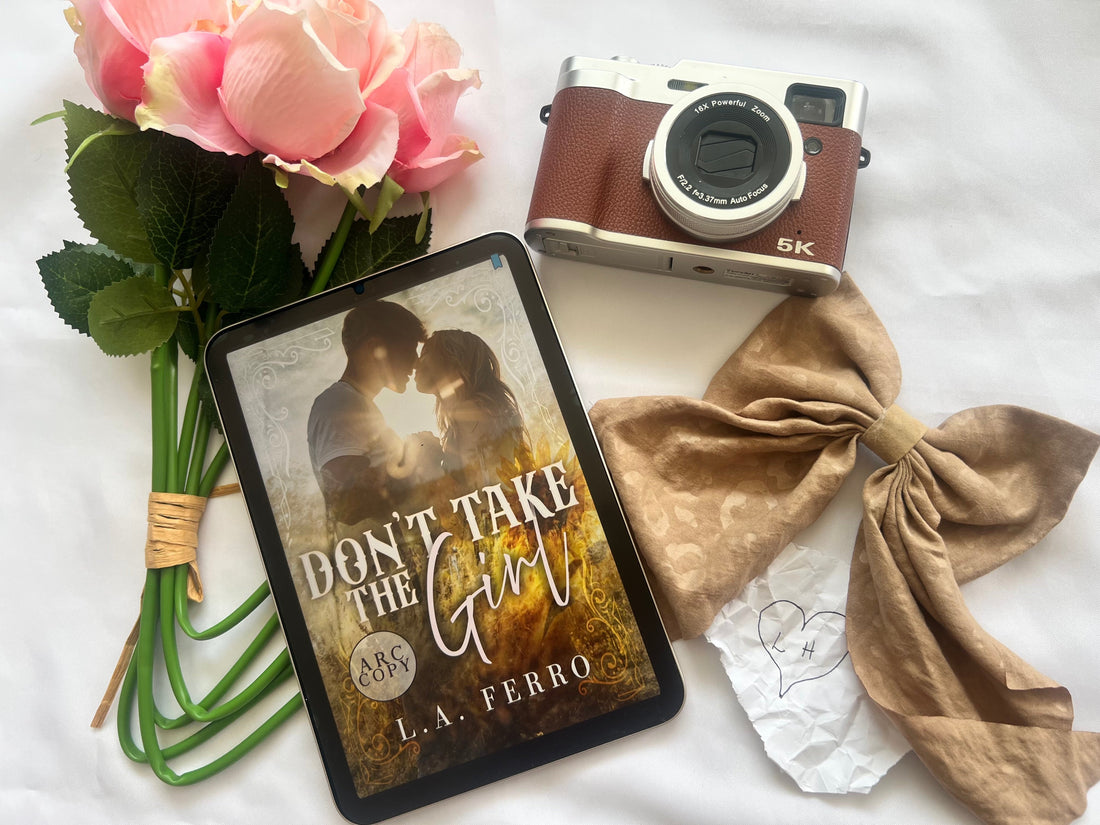 Don’t Take the Girl by L.A. Ferro with flowers, vintage camera, and romantic props on white background.